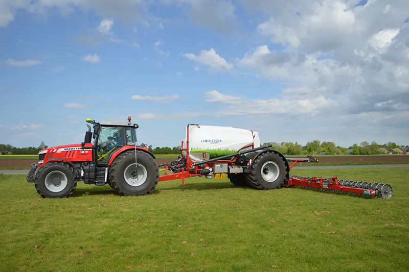 Roter Massey-Ferguson-Traktor mit weißem Liquiliser-Tank und Injektionsgerät auf Grünland.