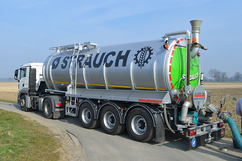 LKW mit silbernem Tankauflieger und der Aufschrift Strauch auf einem Feldweg.